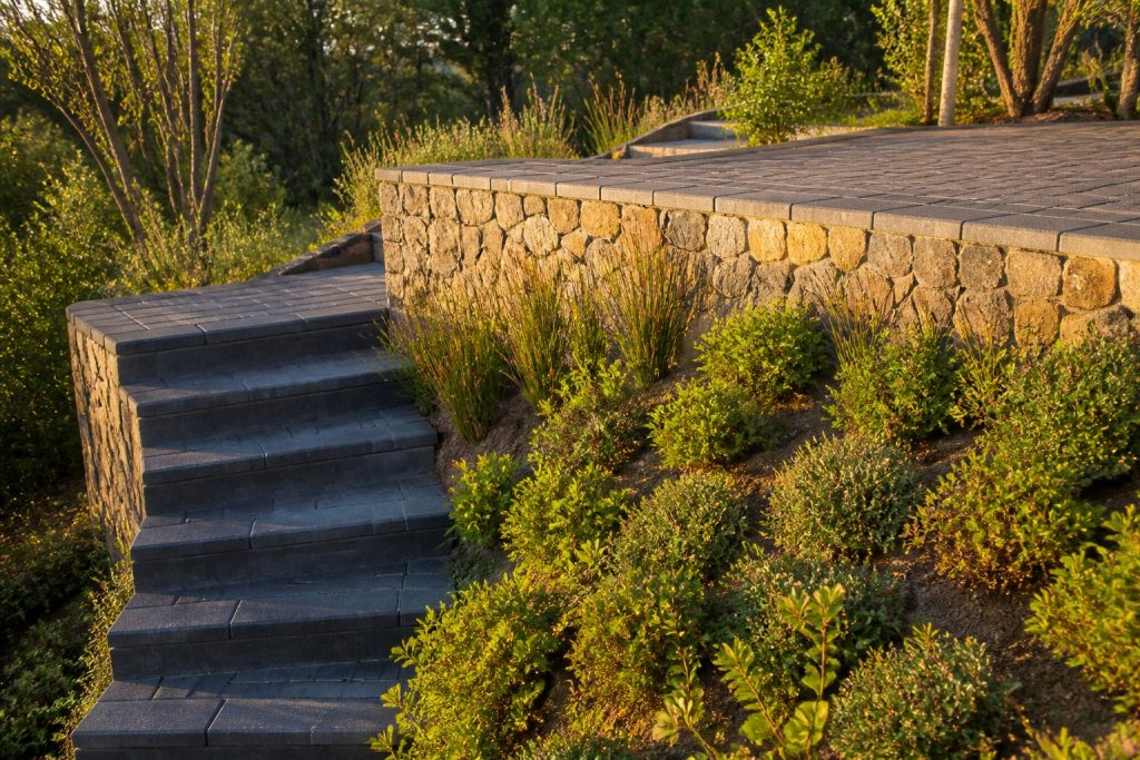 Terraced sloped garden in Cape Town with stone retaining walls, paved terrace and broad brick steps